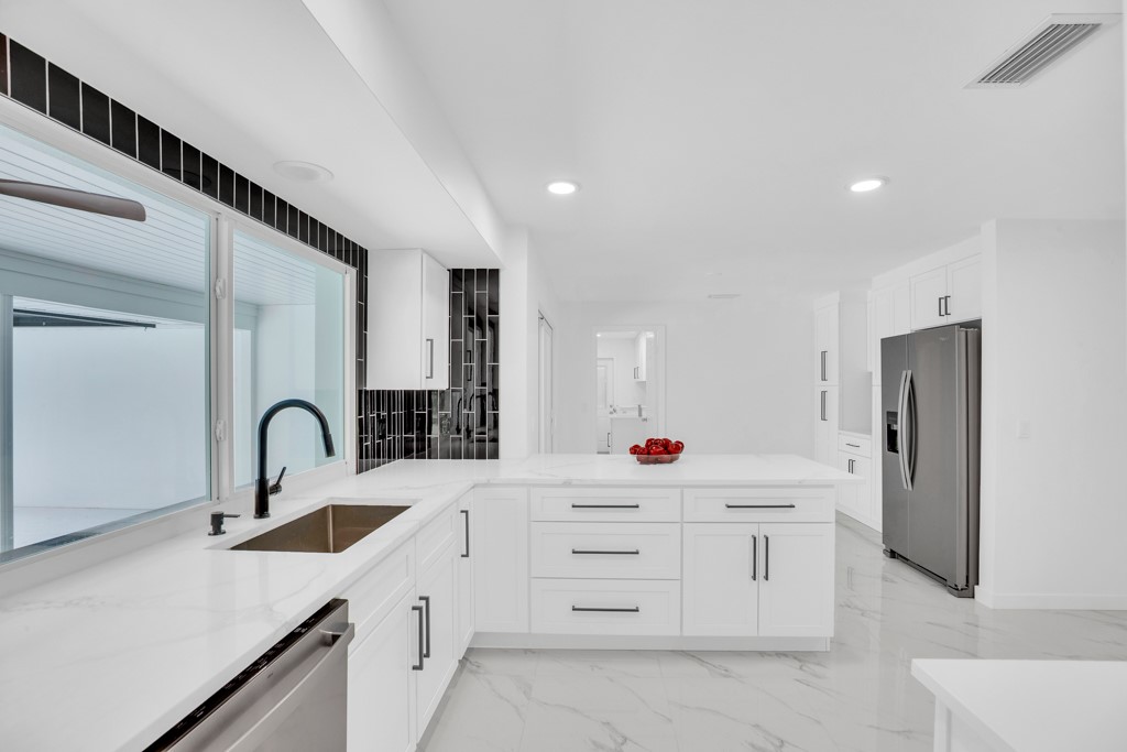 4384 2nd Square Southwest Vero Beach, FL 32968 - Photo 12 of 36 a kitchen with a sink white cabinets and stainless steel appliances