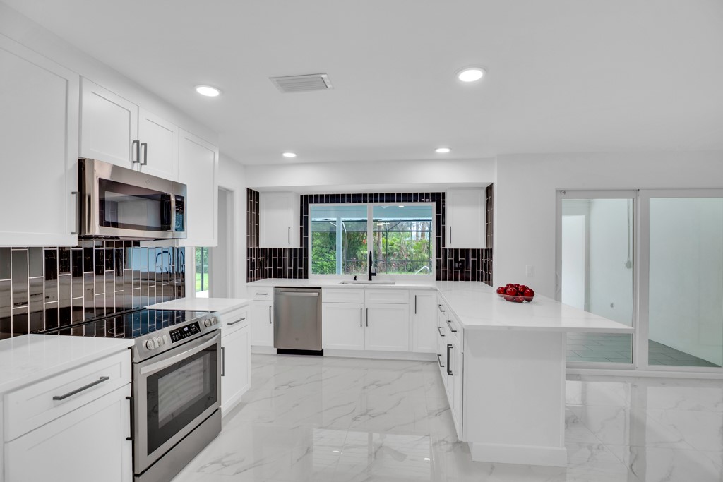 4384 2nd Square Southwest Vero Beach, FL 32968 - Photo 10 of 36 a large white kitchen with a large window a sink and a stove top oven