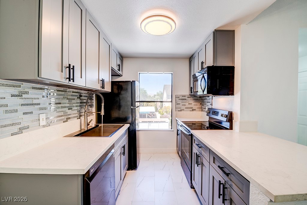 Kitchen with decorative backsplash, electric range, gray cabinetry, and dishwashing machine
