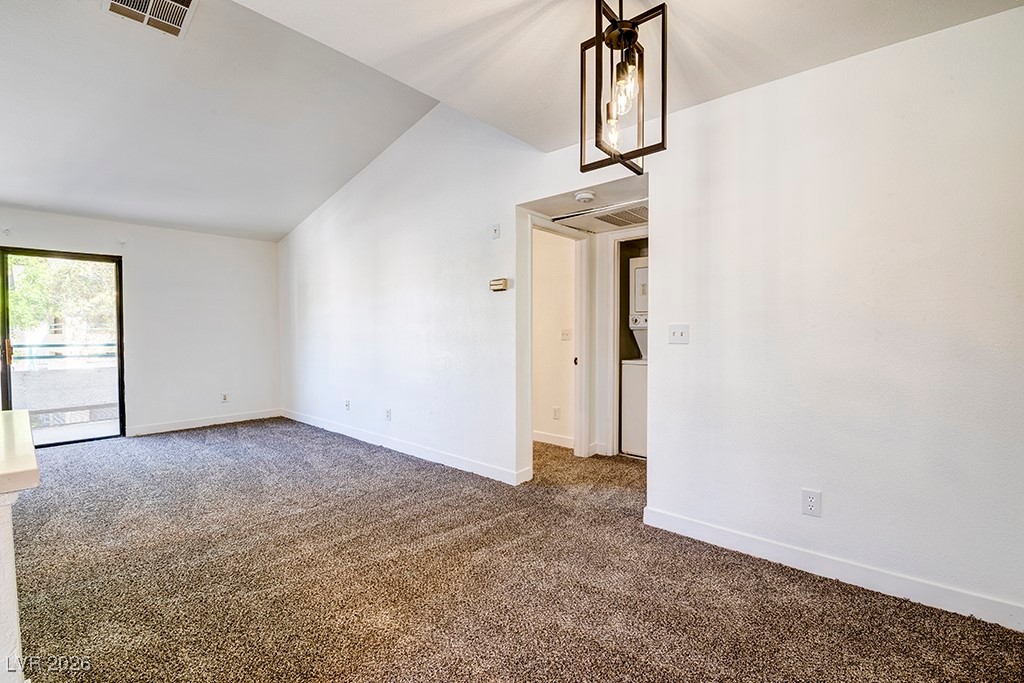 5121 South Lindell Road, Unit 206 Las Vegas, NV 89118 - Photo 11 of 34 Carpeted spare room with vaulted ceiling and stacked washing machine and dryer