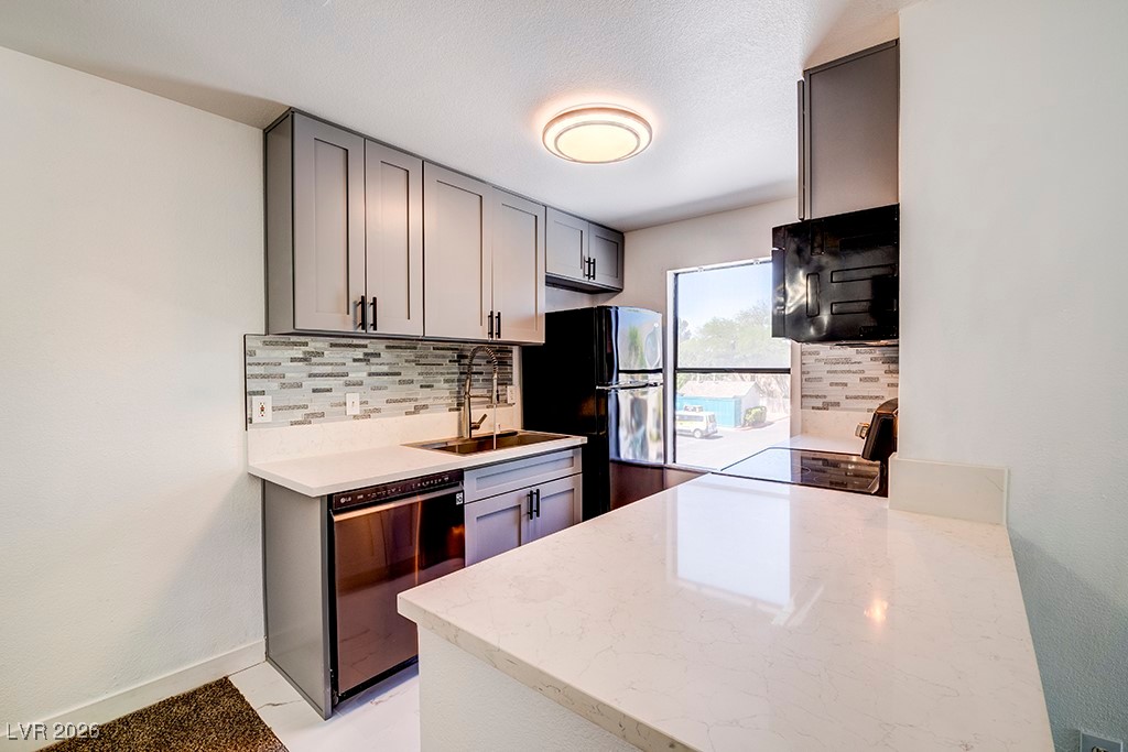 5121 South Lindell Road, Unit 206 Las Vegas, NV 89118 - Photo 4 of 34 Kitchen featuring backsplash, black appliances, light stone counters, and gray cabinetry