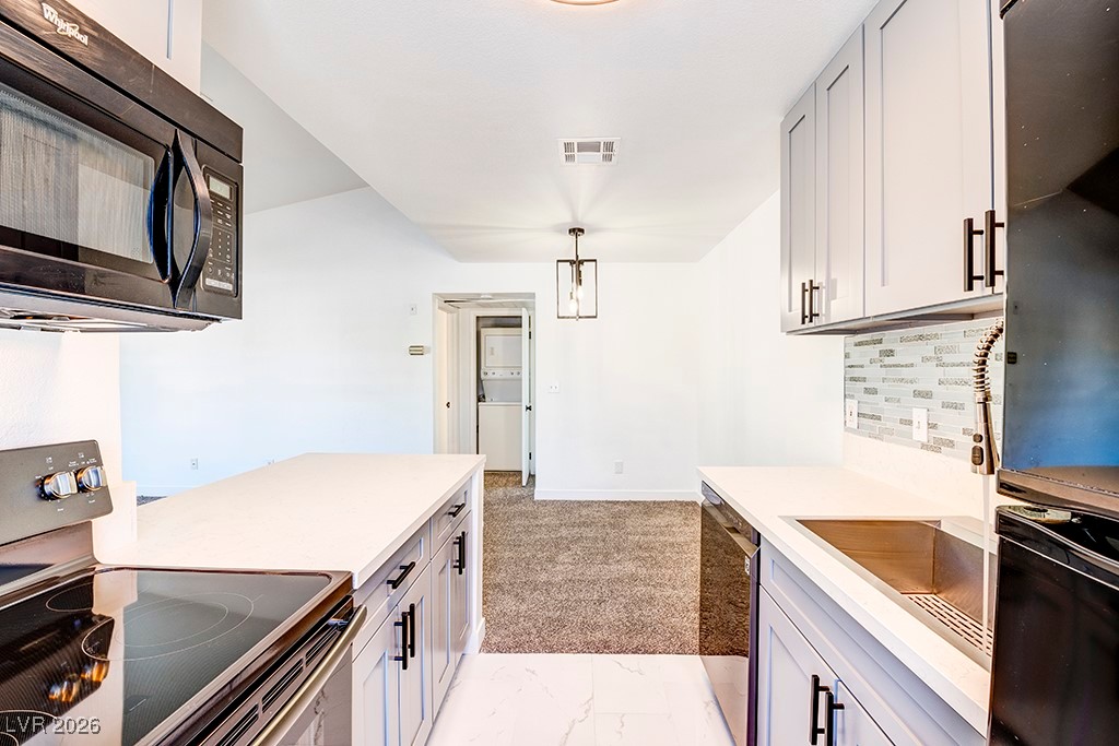 5121 South Lindell Road, Unit 206 Las Vegas, NV 89118 - Photo 5 of 34 Kitchen with black appliances, tasteful backsplash, pendant lighting, light marble finish floors, and washer / clothes dryer