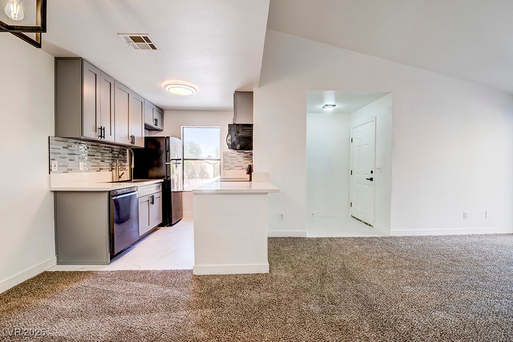 5121 South Lindell Road, Unit 206 Las Vegas, NV 89118 - Photo 32 of 34 Kitchen with gray cabinets, light carpet, backsplash, black appliances, and open floor plan