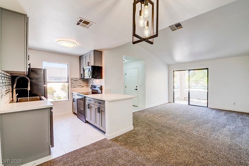 5121 South Lindell Road, Unit 206 Las Vegas, NV 89118 - Photo 33 of 34 Kitchen with gray cabinetry, decorative backsplash, electric range, open floor plan, and black microwave