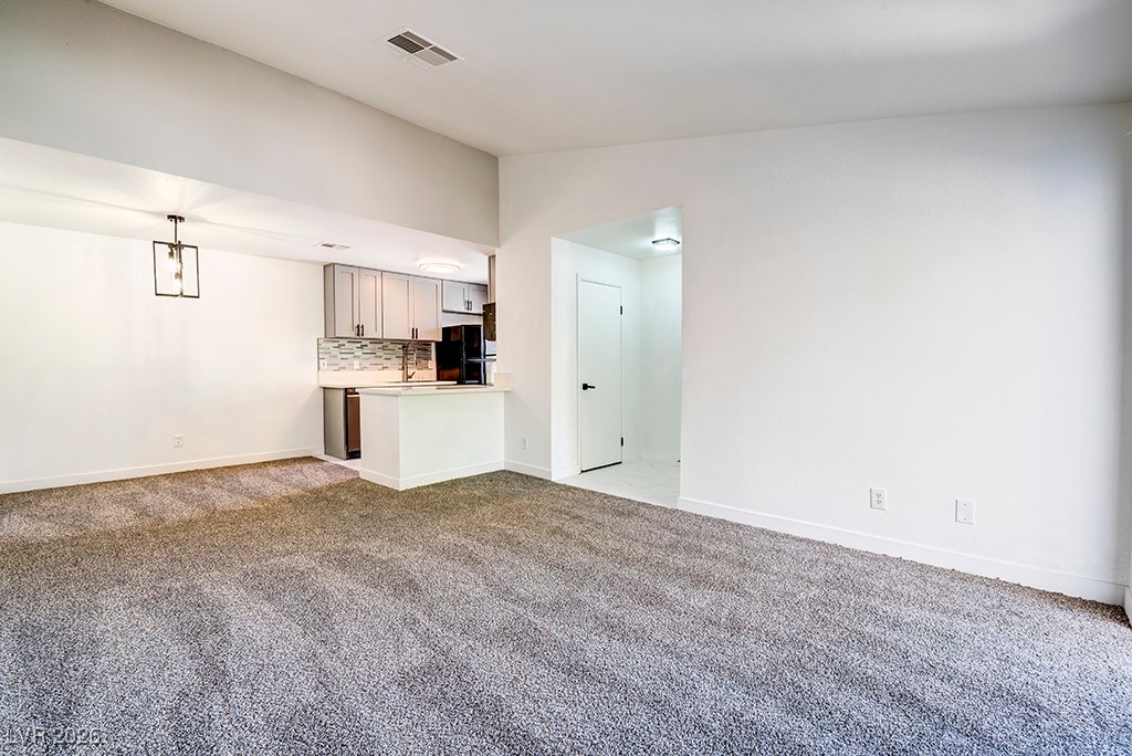 5121 South Lindell Road, Unit 206 Las Vegas, NV 89118 - Photo 7 of 34 Unfurnished living room with carpet flooring and vaulted ceiling