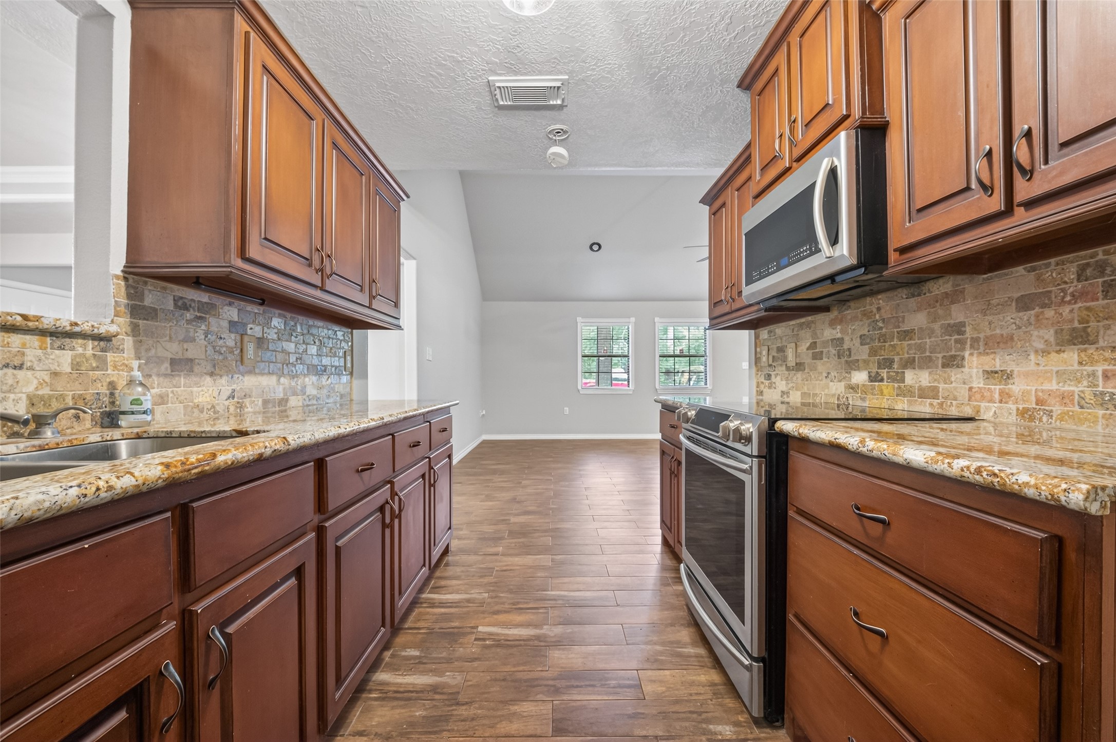 1007 West Cedar River Road Conroe, TX 77316 - Photo 14 of 48 a kitchen with stainless steel appliances granite countertop a sink and dishwasher a stove top oven with wooden floor