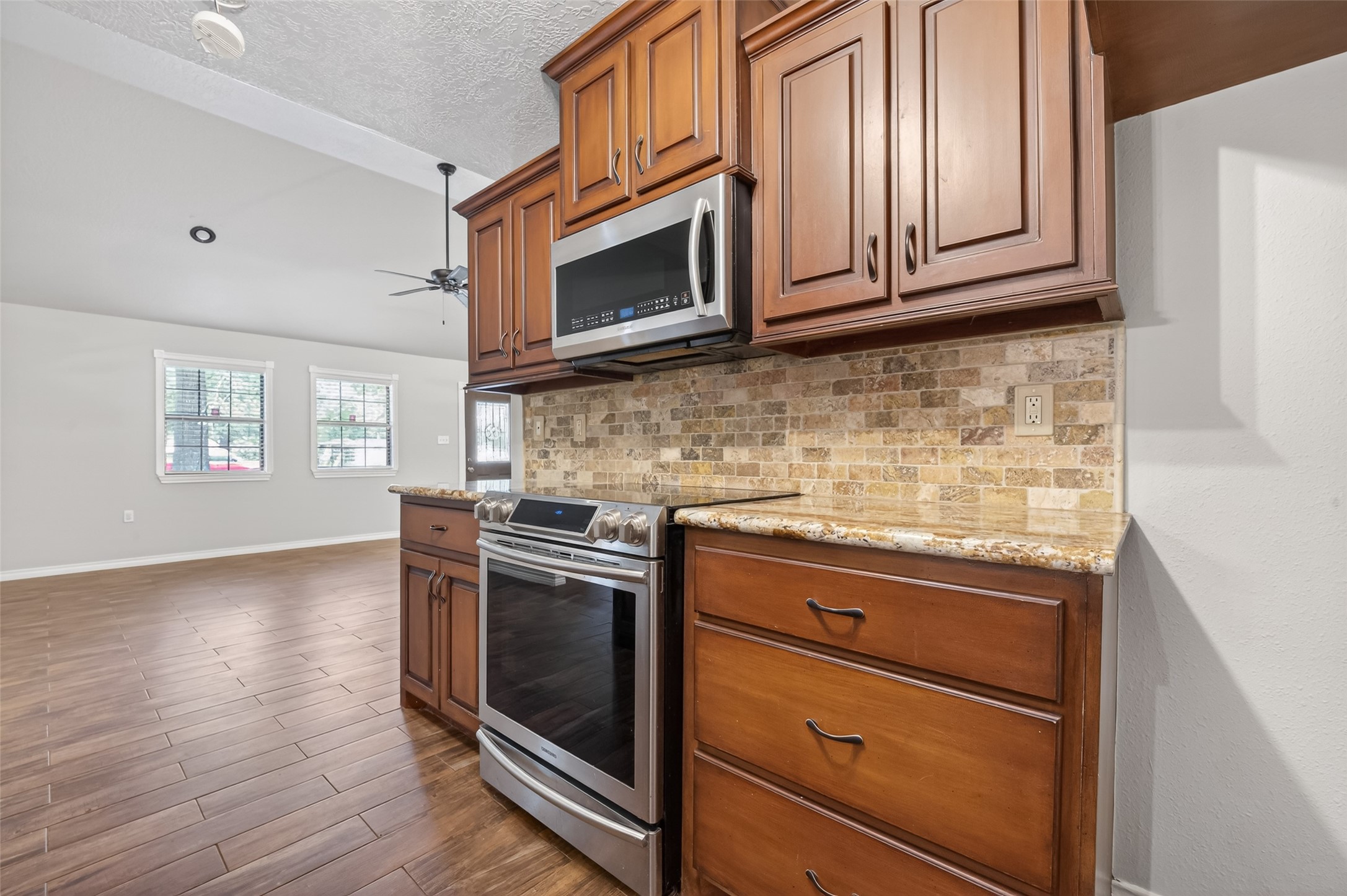 1007 West Cedar River Road Conroe, TX 77316 - Photo 15 of 48 a kitchen with granite countertop wooden cabinets stainless steel appliances and a window