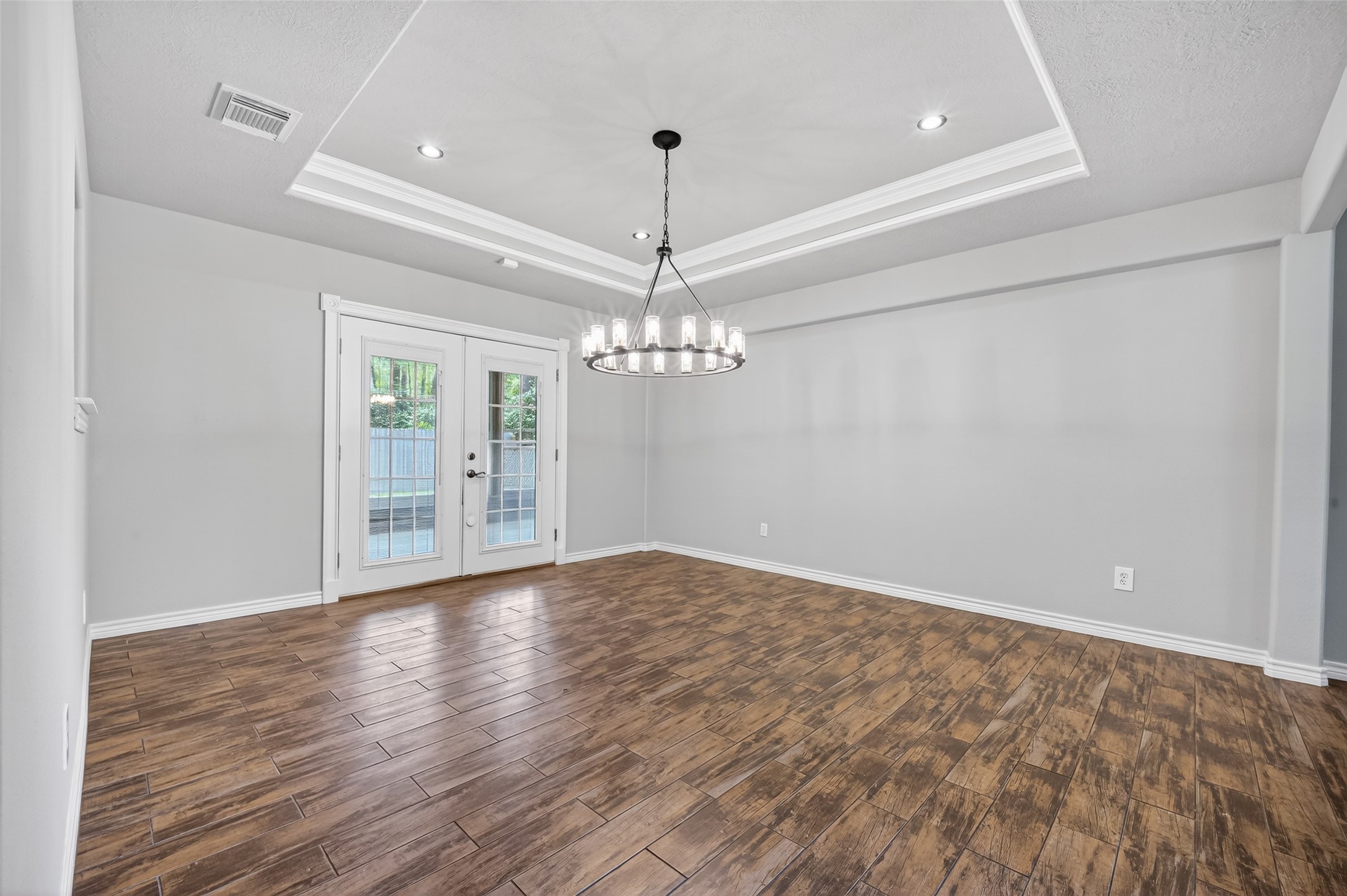 1007 West Cedar River Road Conroe, TX 77316 - Photo 19 of 48 a view of an empty room with chandelier and wooden floor