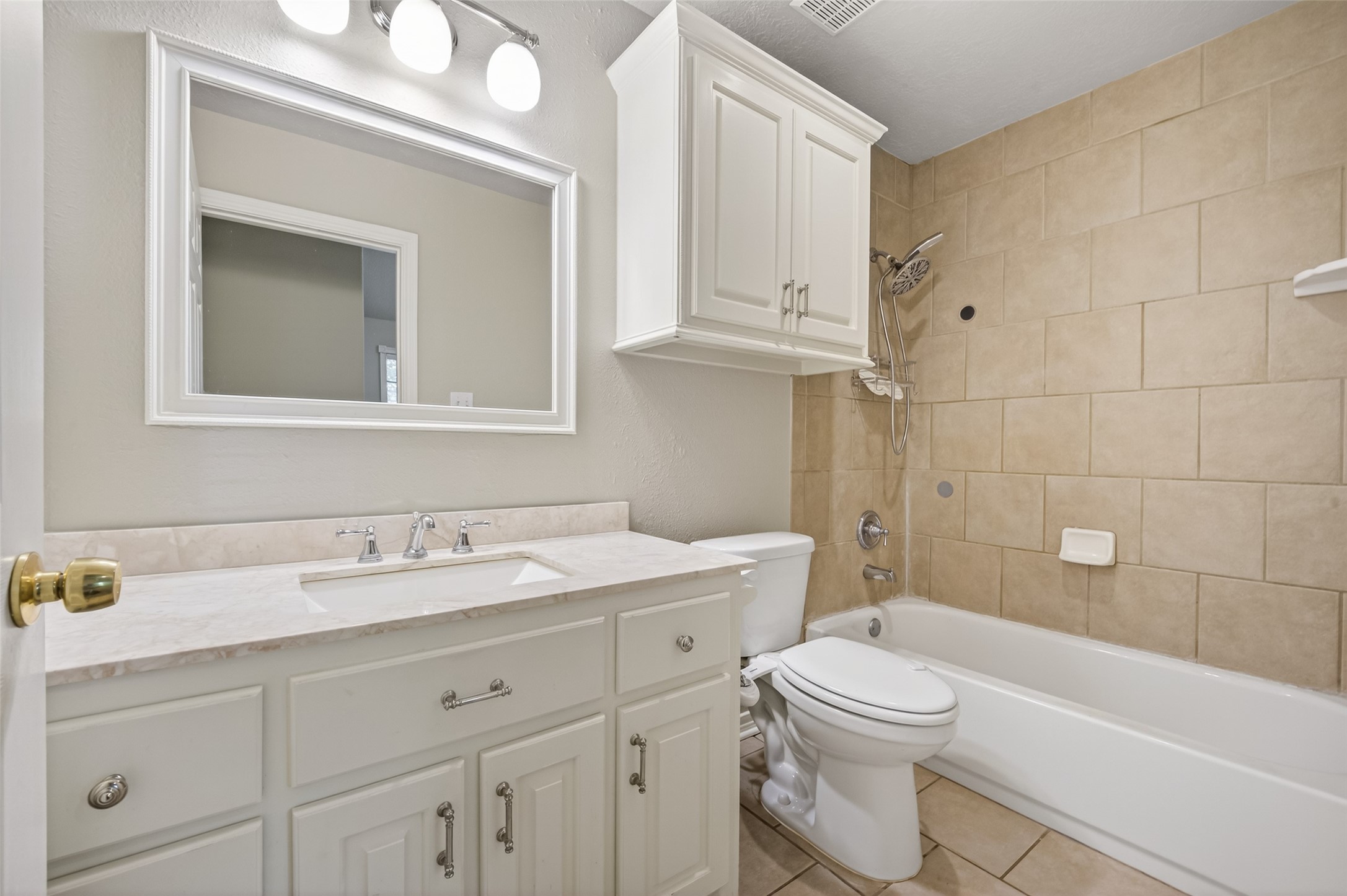 1007 West Cedar River Road Conroe, TX 77316 - Photo 33 of 48 This primary bathroom features a clean, modern design with a white vanity and ample storage. It includes a bathtub/shower with beige tile surround, a large mirror, and overhead lighting for a bright, inviting space.