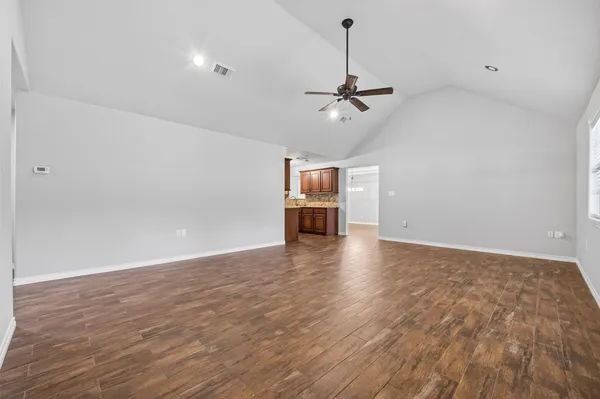 a view of empty room with wooden floor and ceiling fan