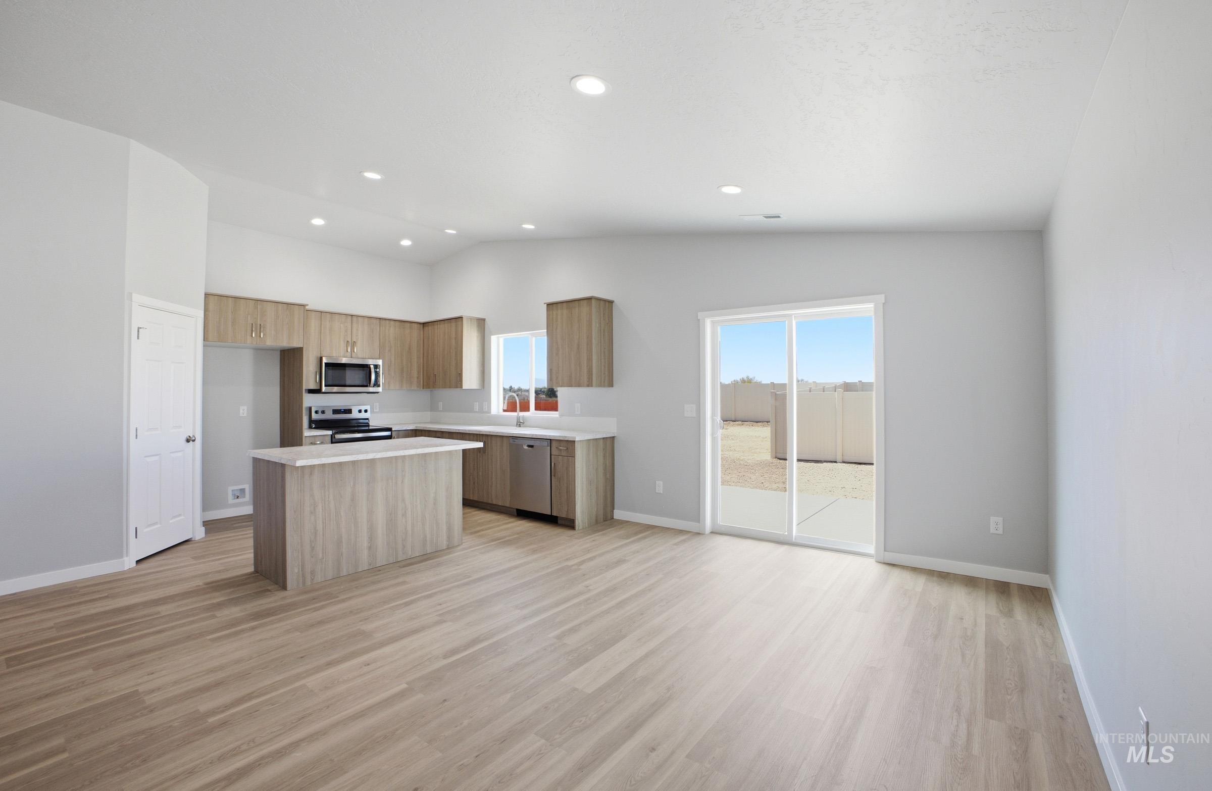 14106 Winding Street Caldwell, ID 83607 - Photo 9 of 18 Open-concept living space featuring wood-finish flooring, a kitchen island with stone-look countertop, stainless steel appliances, recessed lighting, and sliding glass doors to the exterior