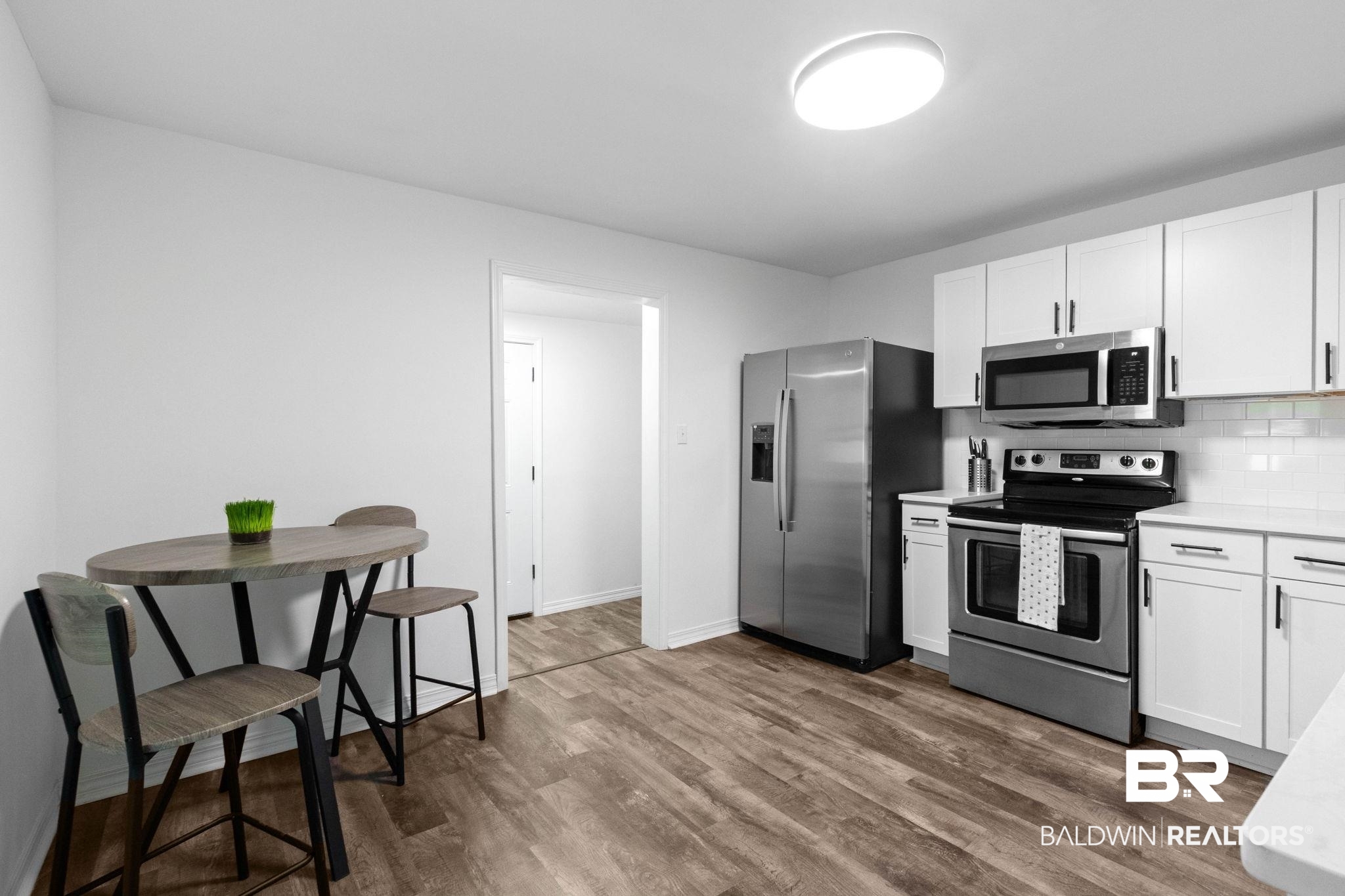128 Bush Avenue Mobile, AL 36604 - Photo 8 of 40 Kitchen featuring stainless steel appliances, white cabinetry, dark wood-style flooring, and decorative backsplash