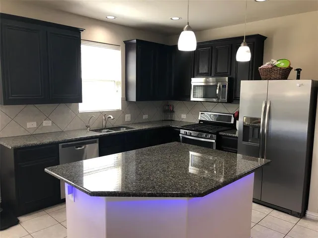 a kitchen with stainless steel appliances granite countertop a sink a microwave a refrigerator and a stove