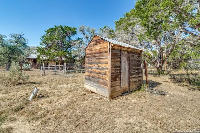 a view of backyard with wooden fence and large trees