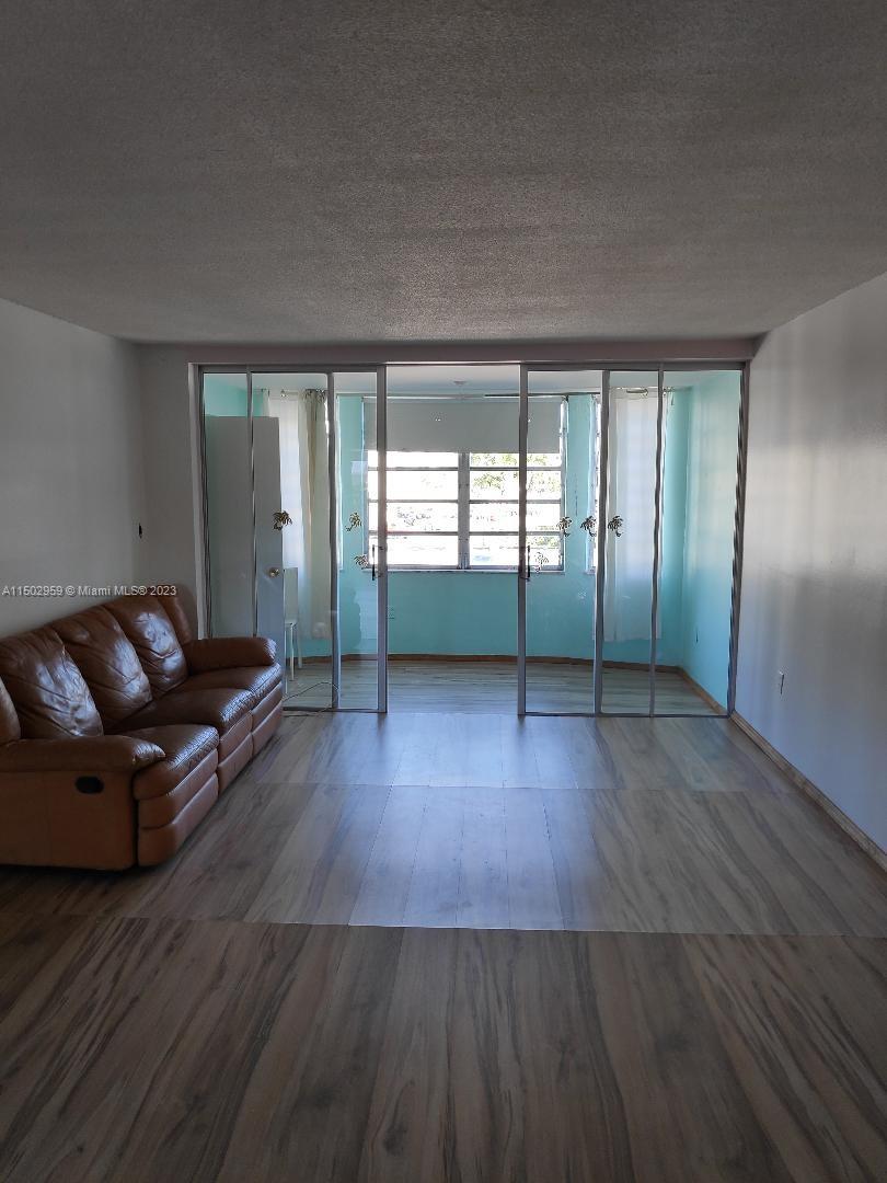 1680 Northeast 191st Street, Unit 2182 Miami, FL 33179 - Photo 3 of 8 an empty room with wooden floor and windows