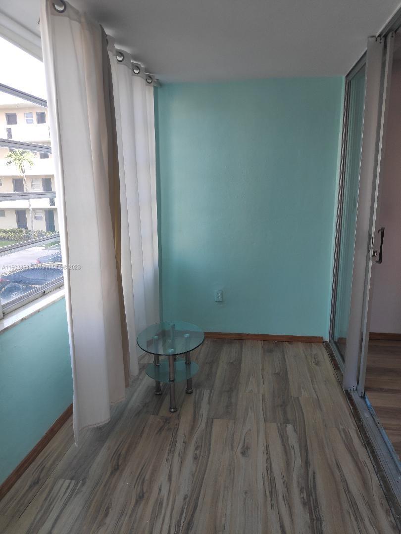 1680 Northeast 191st Street, Unit 2182 Miami, FL 33179 - Photo 5 of 8 a view of an empty room with wooden floor and a window