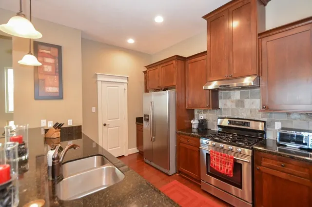 a kitchen with stainless steel appliances granite countertop a sink stove and refrigerator