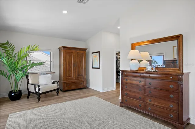 a bedroom with a bed a dresser and next to a window