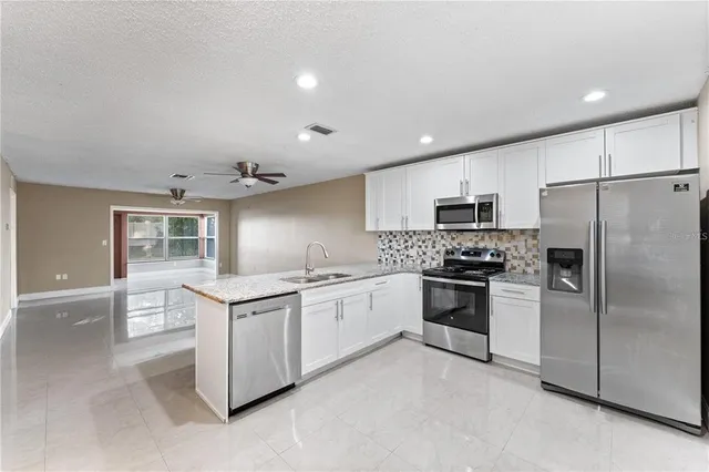 a kitchen with granite countertop white cabinets and stainless steel appliances