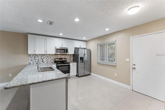 a kitchen with refrigerator a microwave a sink and cabinets