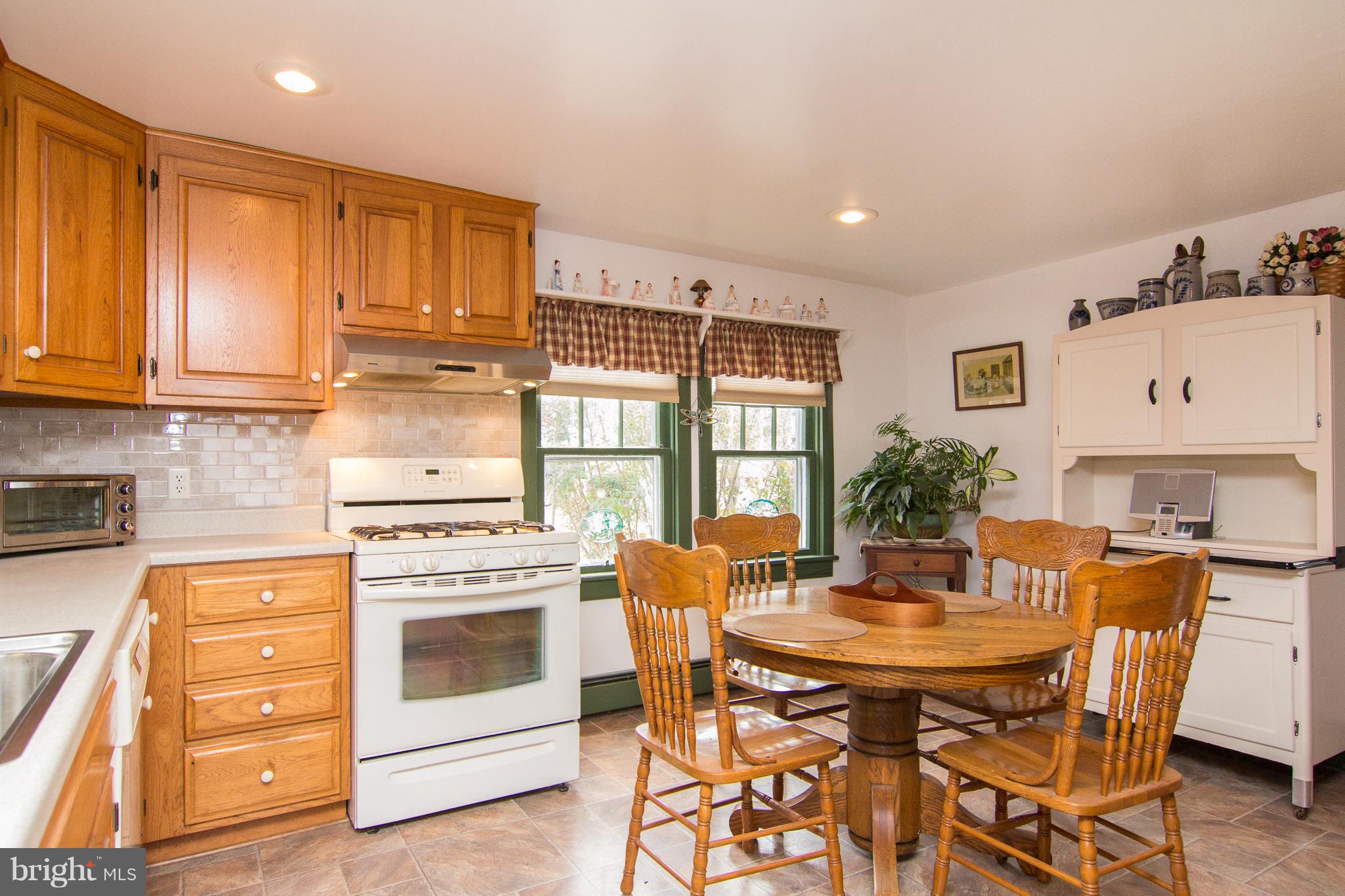 3358 Uniontown Road Westminster, MD 21158 - Photo 10 of 30 a kitchen with stainless steel appliances kitchen island granite countertop a stove a sink a dining table and chairs with wooden floor