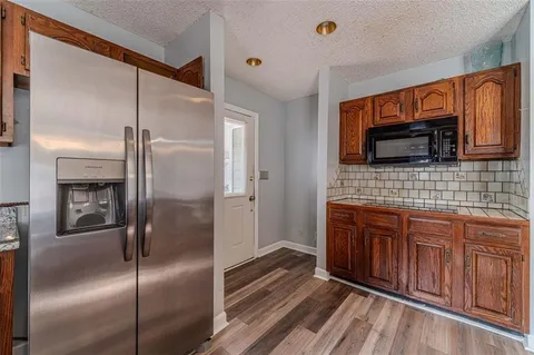 an empty room with wooden floor fireplace and windows