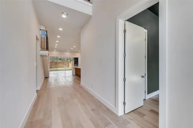 a view of a hallway with wooden floor kitchen view and a refrigerator in a room