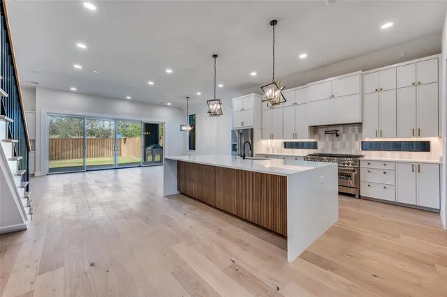 a large kitchen with stainless steel appliances granite countertop a large counter top a sink and a refrigerator