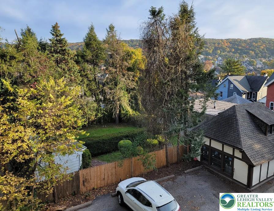 444 West 3rd Street, Unit 9 Bethlehem, PA 18015 - Photo 15 of 16 Mature trees frame a private backyard, offering serene views of distant hills and neighboring rooftops.