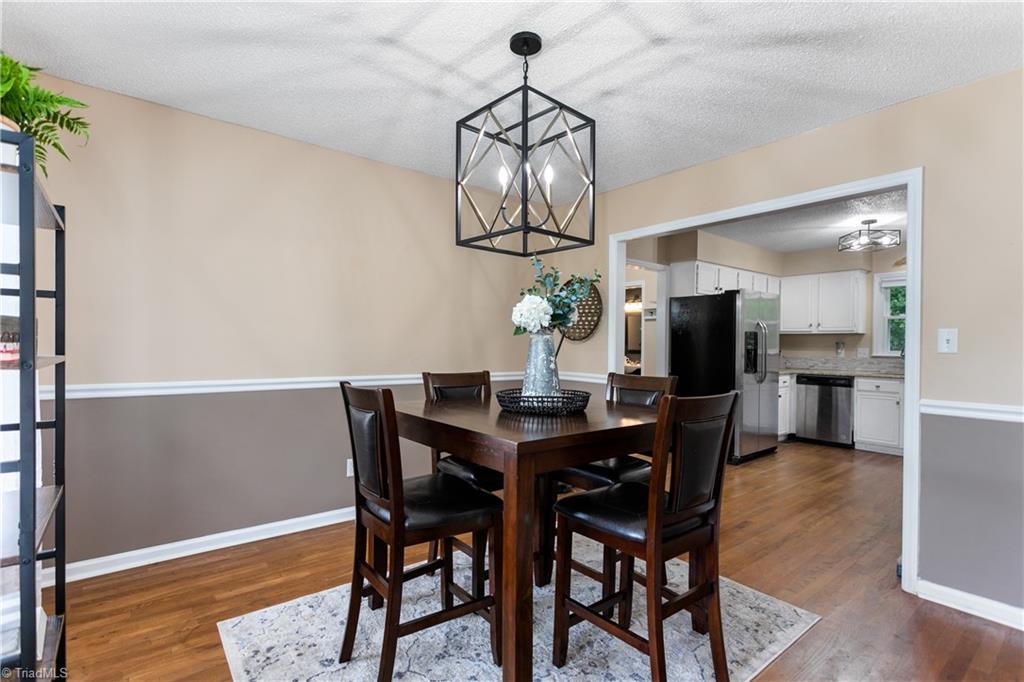 7105 Harper Ridge Court Oak Ridge, NC 27310 - Photo 7 of 23 Dining area with large cased opening into the kitchen. Updated light fixtures, hardwood floors.