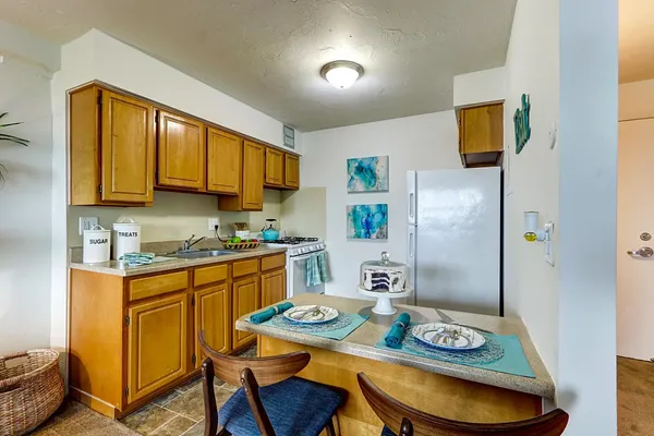 a kitchen with stainless steel appliances granite countertop a sink a stove a refrigerator with a dining table and chairs