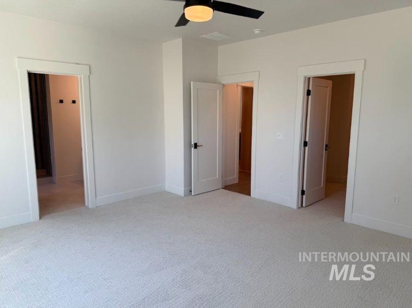 755 West Wrangler Street Meridian, ID 83646 - Photo 9 of 35 Spacious room featuring light-toned carpeting, crisp white walls, a ceiling fan with integrated lighting, and multiple paneled doors with dark hardware