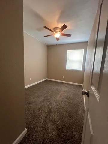 an empty room with windows and fan