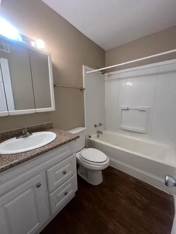 a bathroom with a granite countertop sink a toilet a mirror and shower