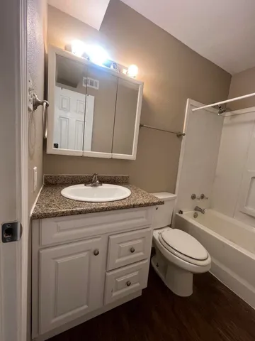 a bathroom with a granite countertop sink toilet a mirror and shower