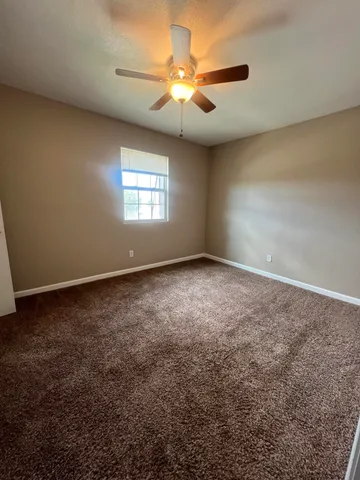 en empty room with windows and chandelier fan