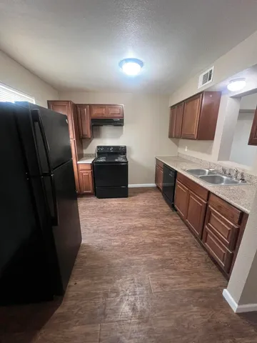 a large kitchen with stainless steel appliances wooden cabinets a stove and a refrigerator
