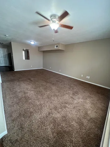 an empty room with a ceiling fan and window
