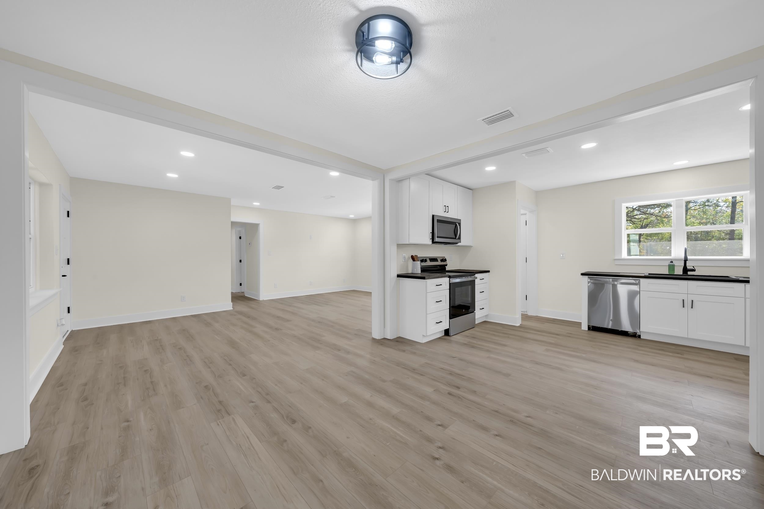 1409 Altair Lane Mobile, AL 36693 - Photo 23 of 23 Kitchen with white cabinets, stainless steel appliances, open floor plan, recessed lighting, and light wood-type flooring