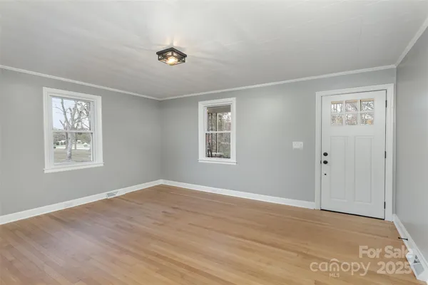a view of an empty room with wooden floor and a window
