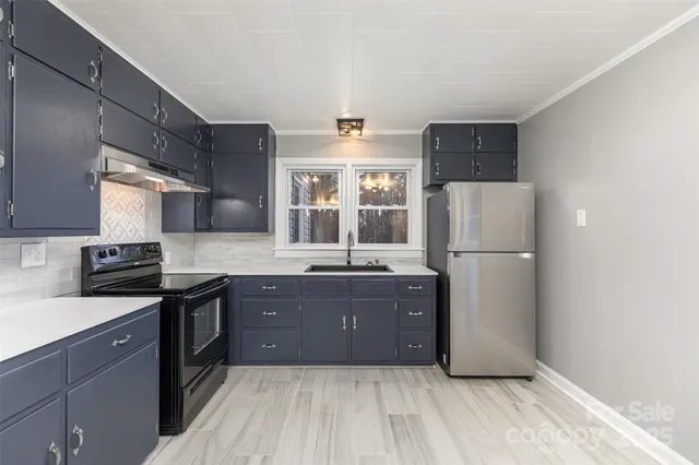 a kitchen with granite countertop a refrigerator a sink a stove and wooden cabinets