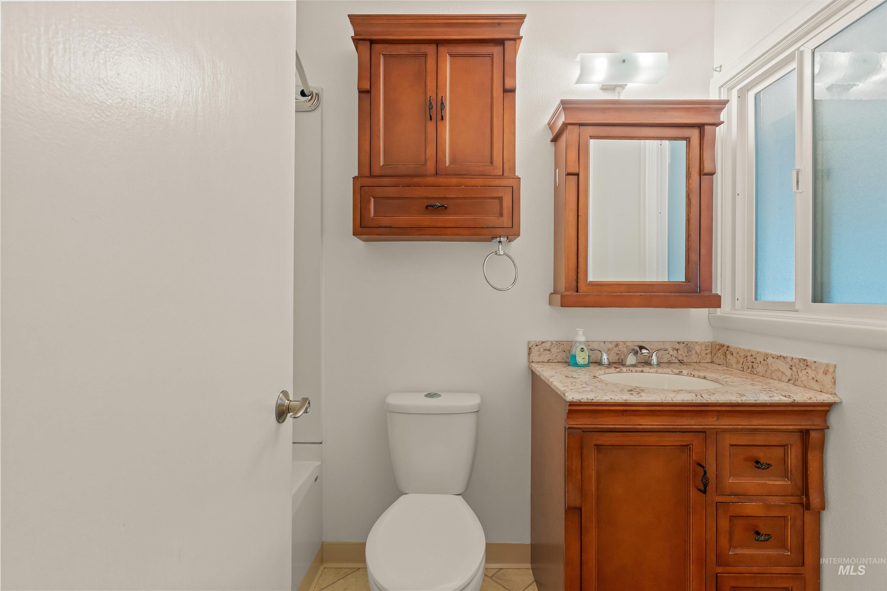 1663 9th Avenue Lewiston, ID 83501 - Photo 29 of 36 Full bathroom featuring a wood-finish vanity with a stone countertop, an integrated sink, and a framed mirror with overhead lighting
