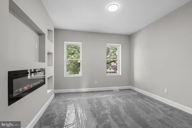 a view of an empty room with a window and fireplace
