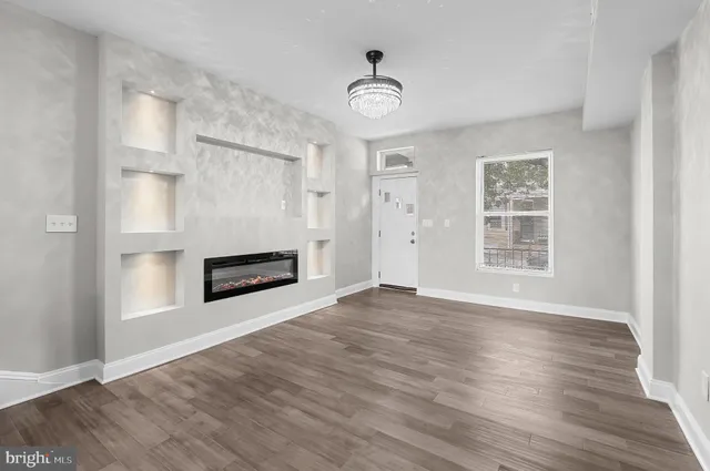 an empty room with wooden floor cabinet and windows