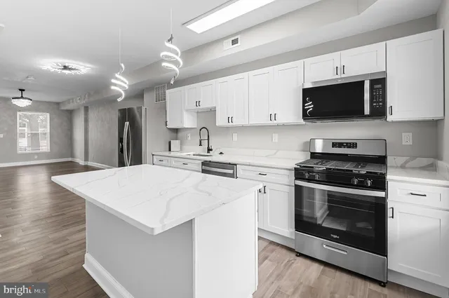 a kitchen with stainless steel appliances a stove microwave and sink