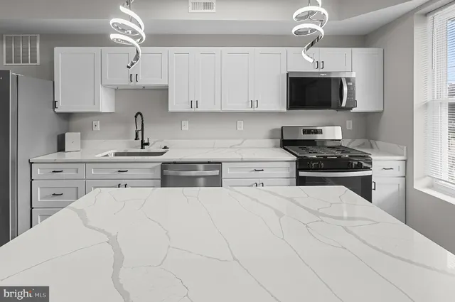 a kitchen with stainless steel appliances a stove sink microwave and cabinets