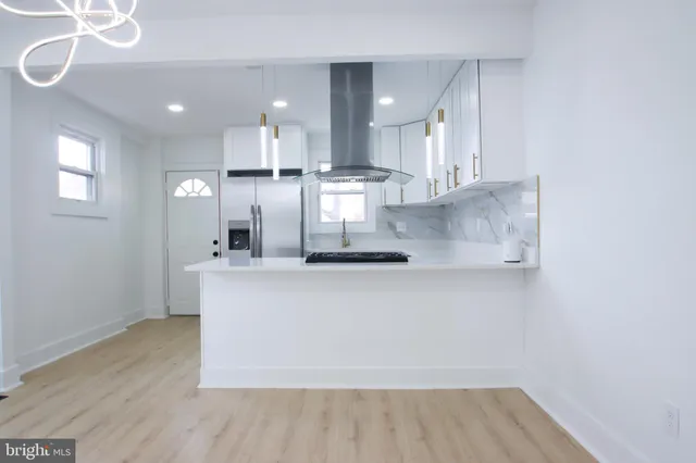 a large kitchen with stainless steel appliances a large counter top a stove and a refrigerator