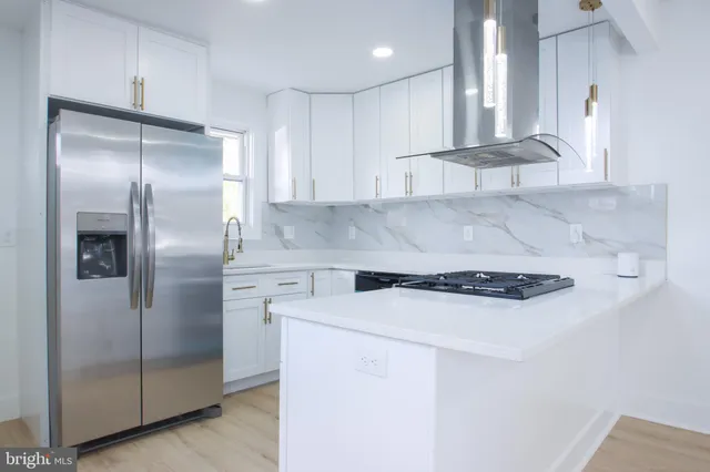 a kitchen with stainless steel appliances granite countertop a refrigerator a sink and white cabinets