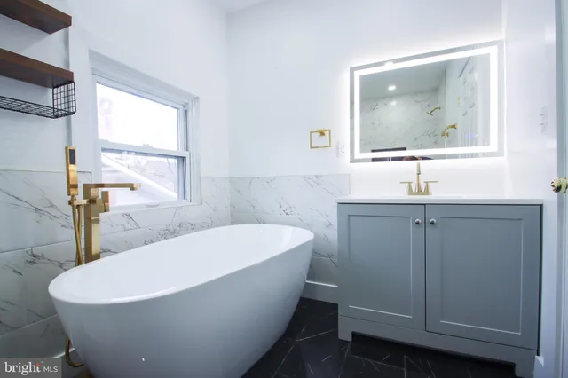 a bathroom with a white tub a sink and mirror