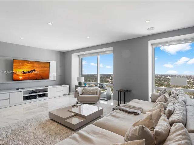 a living room with stainless steel appliances furniture a rug and a kitchen view